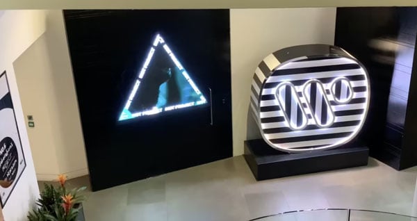 Custom LED triangle playing a music video beside the illuminated Warner Music Group logo in the reception of a Warner office