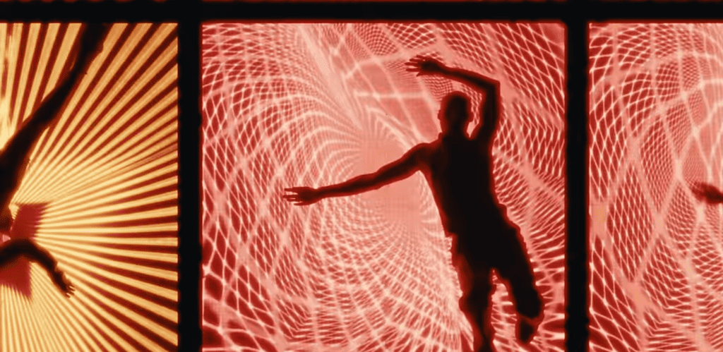 Dancer in silhouette against red and orange radial LED patterns in the Shygirl thicc video, the LED surface behind and beneath the performer