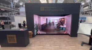 Three‑sided immersive LED room with matching LED floor at a property exhibition stand.