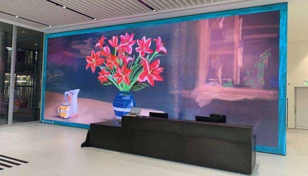 Corporate lobby with a large LED display showing abstract art and welcome messages.