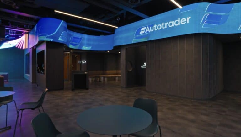 LED ribbon with undulating wave geometry running above the AutoTrader café, showing the curved profile from seating level