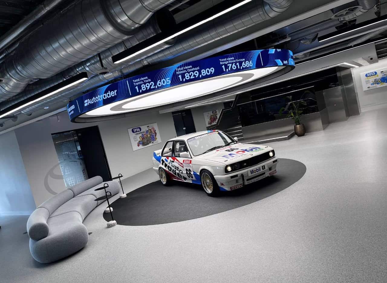 AutoTrader Manchester HQ – LED halo ticker showing live vehicle listing views suspended above the reception area