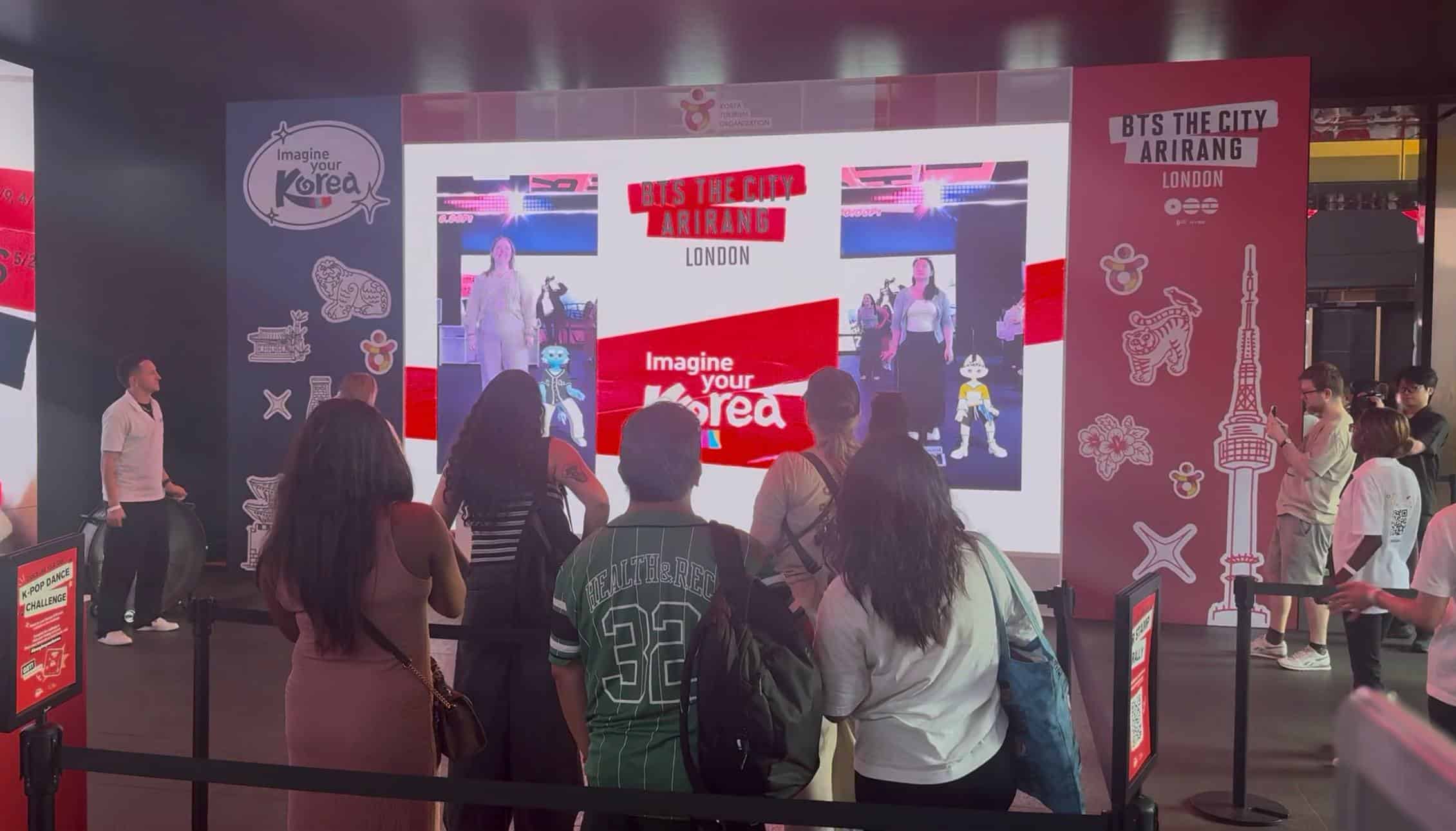 Crowd watching the two-player K-pop dance challenge scored live on Dynamo's rental LED wall at the BTS The City Arirang London activation, Outernet London