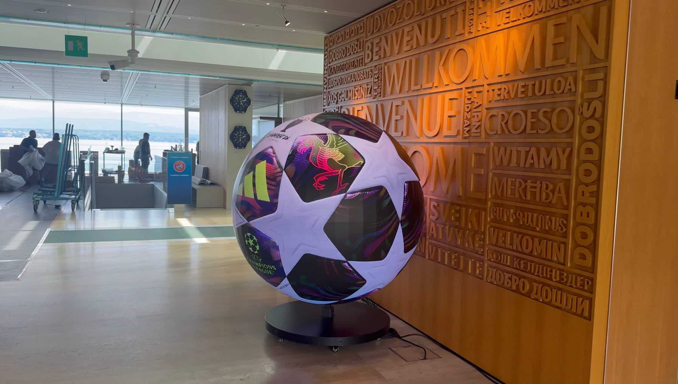 Dynamo's hire LED sphere beside the carved welcome wall at UEFA's headquarters, with Lake Geneva behind